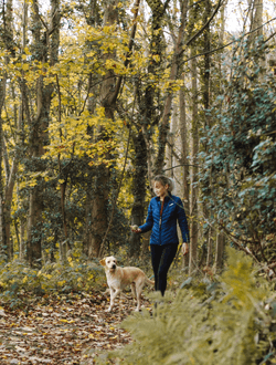 Woman playing fetch with her dog in the woods